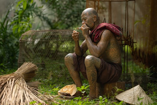 A tattooed elderly man smoking a cigarette in the garden photo