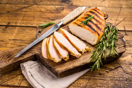 Grilled and sliced Chicken breasts on cutting board, grilled poultry meat, top view, wooden background. photo