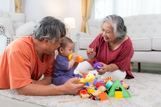 Grandparents and their little grandchild play happily in the living room of the house photo