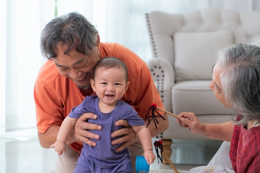 Grandparents and their little grandchild play happily in the living room of the house photo