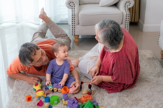 Grandparents and their little grandchild play happily in the living room of the house photo