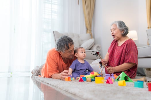 Grandparents and their little grandchild play happily in the living room of the house photo