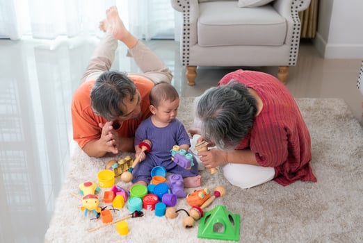Grandparents and their little grandchild play happily in the living room of the house photo