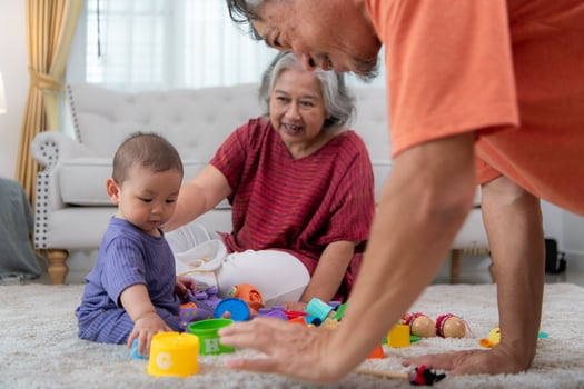 Grandparents and their little grandchild play happily in the living room of the house photo