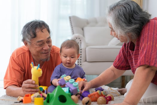 Grandparents and their little grandchild play happily in the living room of the house photo