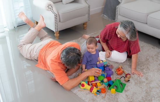 Grandparents and their little grandchild play happily in the living room of the house photo