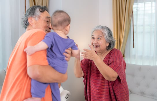 Grandparents and their little grandchild play happily in the living room of the house photo