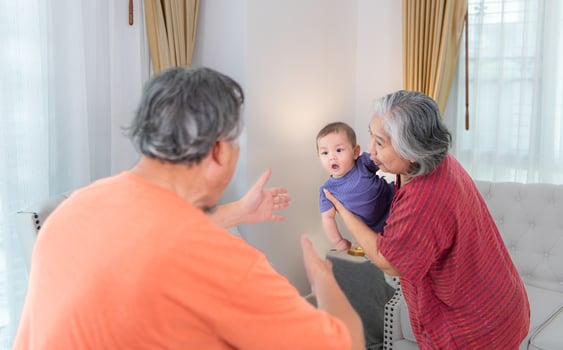 Grandparents and their little grandchild play happily in the living room of the house photo