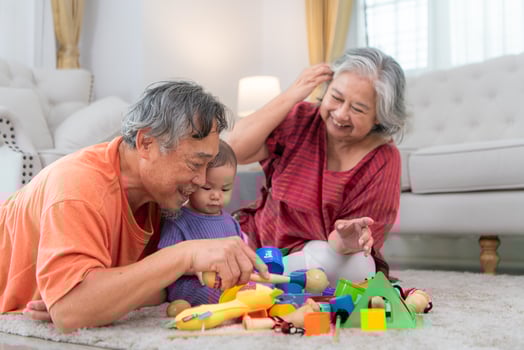 Grandparents and their little grandchild play happily in the living room of the house photo