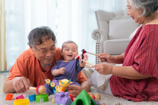 Grandparents and their little grandchild play happily in the living room of the house photo