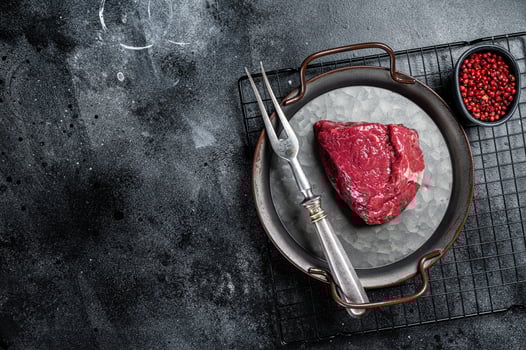 Piece of raw rump steak prepared for cooking. Black background. Top view. Copy space photo