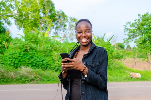 pretty young african woman smiling and using her mobile phone outdoor photo