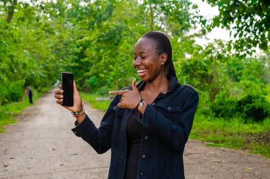 pretty young african woman smiling and using her mobile phone outdoor photo
