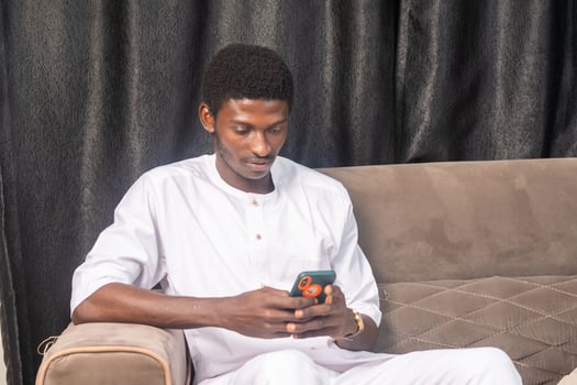 African American man using smartphone at home. Black Male Freelancer texting on mobile phone in Living room photo