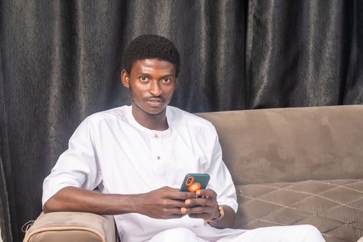 African American man using smartphone at home. Black Male Freelancer texting on mobile phone in Living room photo