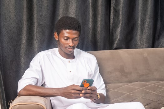 African American man using smartphone at home. Black Male Freelancer texting on mobile phone in Living room photo