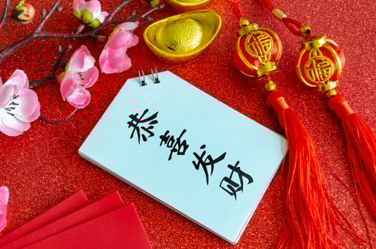 Top view of Chinese New Year saying Gong Xi Fa Cai on white notepad with Chinese New Year decoration background photo