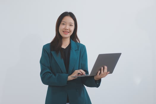 Attractive elegant young asian business woman using digital tablet standing on isolated background. Happy young latin female formal black suit holding tablet gadget working service with customer photo