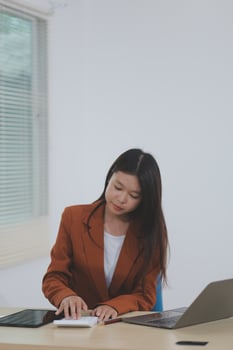 Happy young asian businesswoman sitting on her workplace in the office. Young woman working at laptop in the office. photo