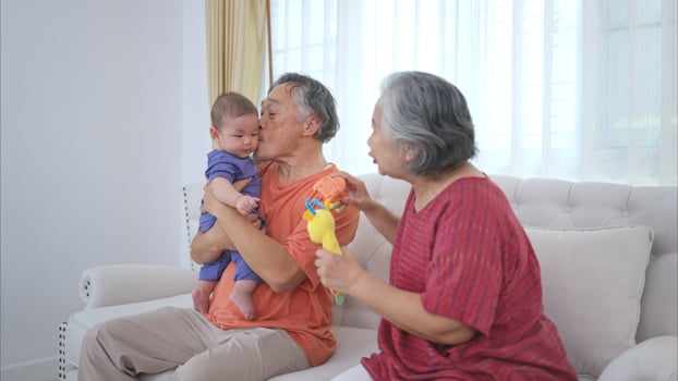 Grandparents and their little grandchild play happily in the living room of the house photo