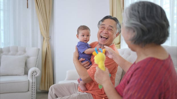 Grandparents and their little grandchild play happily in the living room of the house photo
