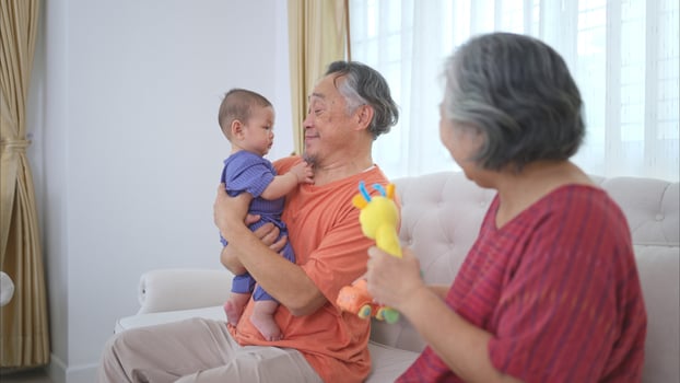 Grandparents and their little grandchild play happily in the living room of the house photo