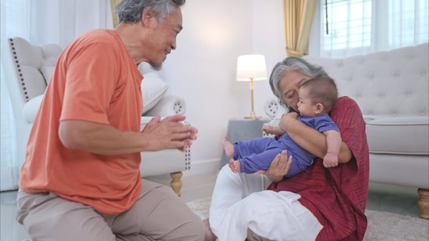 Grandparents and their little grandchild play happily in the living room of the house photo