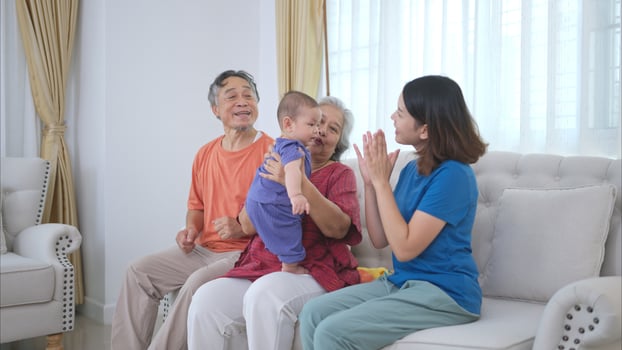 Grandparents and parents with their little child play happily in the living room of the house photo