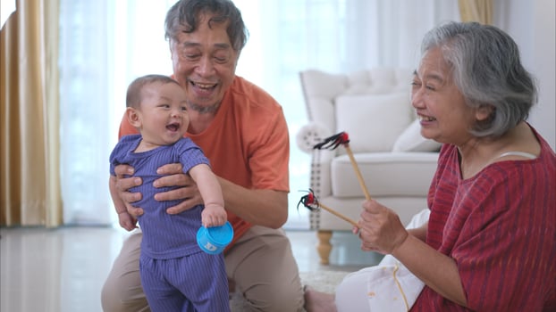 Grandparents and their little grandchild play happily in the living room of the house photo