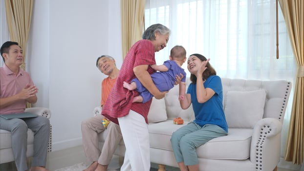 Grandparents and parents with their little child play happily in the living room of the house photo