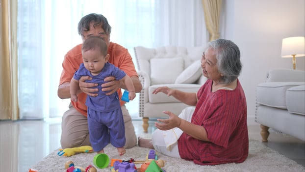 Grandparents and their little grandchild play happily in the living room of the house photo