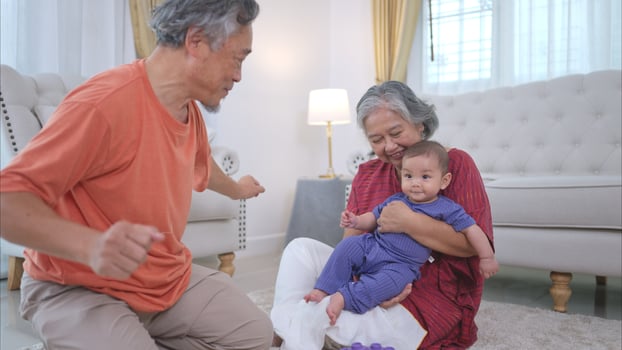 Grandparents and their little grandchild play happily in the living room of the house photo