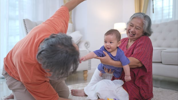 Grandparents and their little grandchild play happily in the living room of the house photo