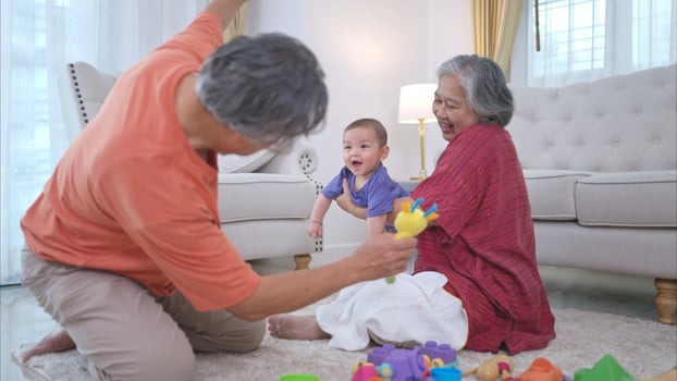 Grandparents and their little grandchild play happily in the living room of the house photo