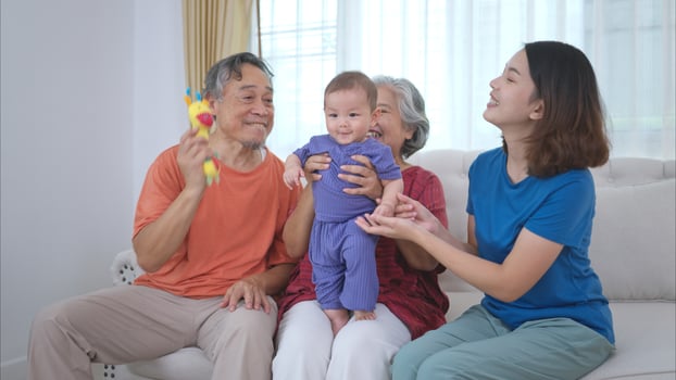 Grandparents and parents with their little child play happily in the living room of the house photo