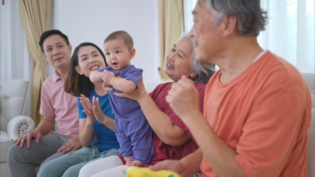 Grandparents and parents with their little child play happily in the living room of the house photo