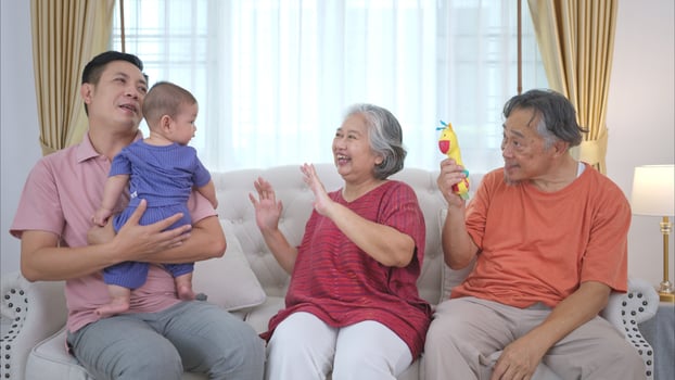 Grandparents and parents with their little child play happily in the living room of the house photo
