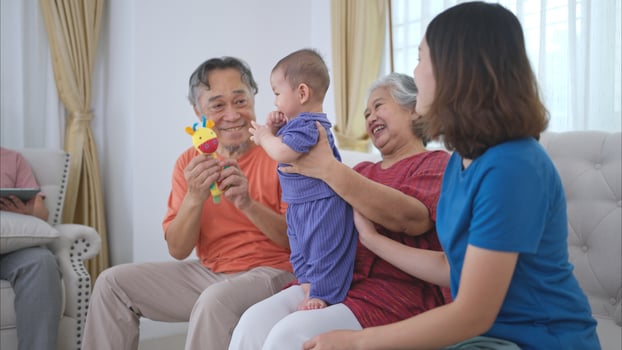 Grandparents and parents with their little child play happily in the living room of the house photo