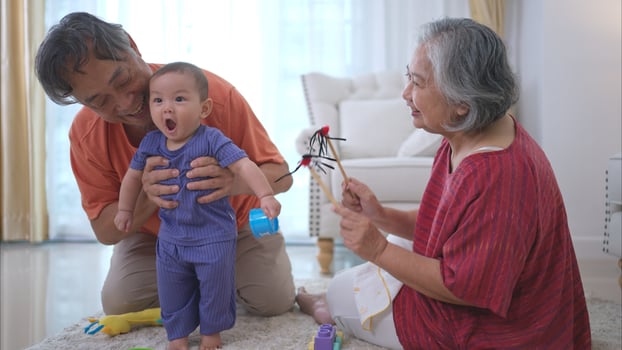 Grandparents and their little grandchild play happily in the living room of the house photo