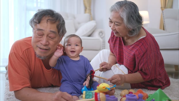 Grandparents and their little grandchild play happily in the living room of the house photo
