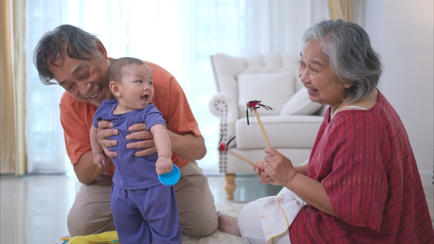 Grandparents and their little grandchild play happily in the living room of the house photo