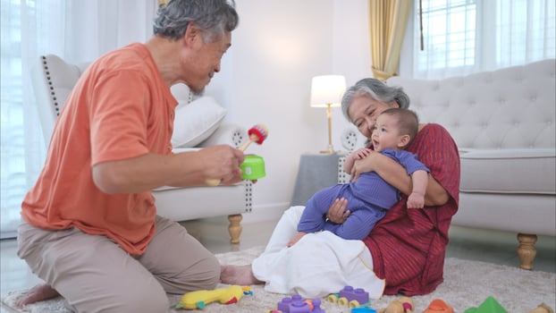 Grandparents and their little grandchild play happily in the living room of the house photo
