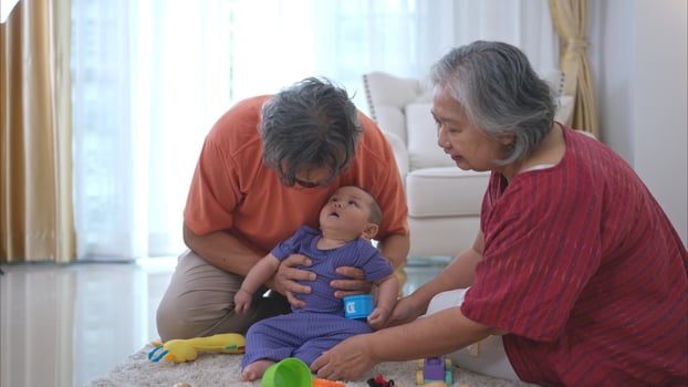Grandparents and their little grandchild play happily in the living room of the house photo