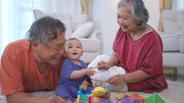 Grandparents and their little grandchild play happily in the living room of the house photo