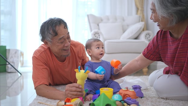 Grandparents and their little grandchild play happily in the living room of the house photo