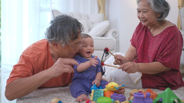 Grandparents and their little grandchild play happily in the living room of the house photo