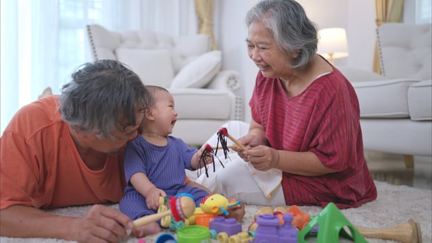 Grandparents and their little grandchild play happily in the living room of the house photo