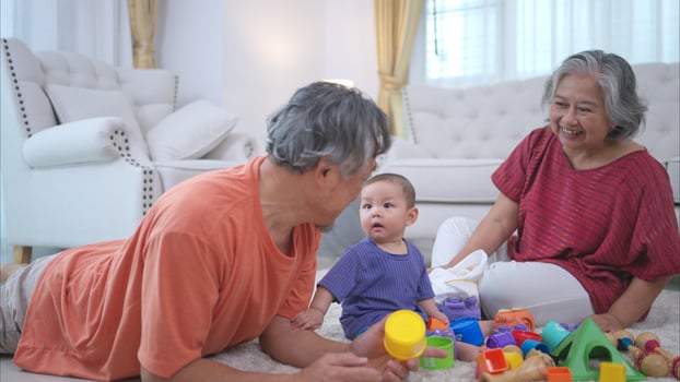 Grandparents and their little grandchild play happily in the living room of the house photo