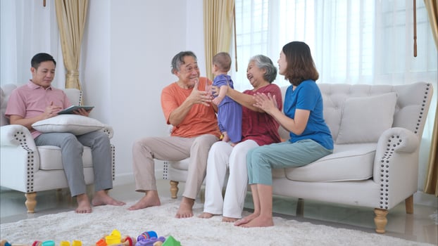 Grandparents and parents with their little child play happily in the living room of the house photo