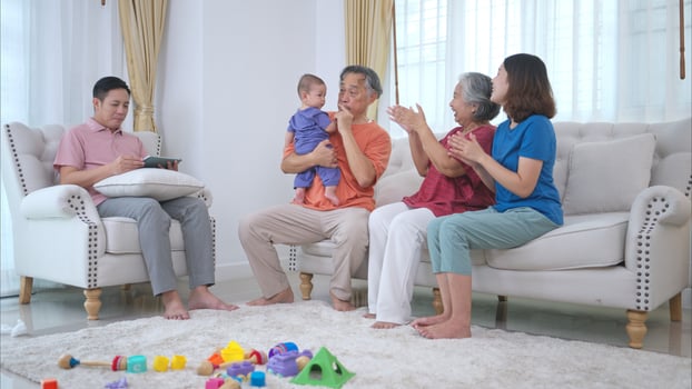 Grandparents and parents with their little child play happily in the living room of the house photo